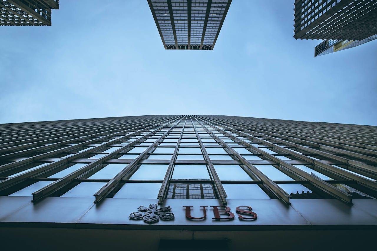 hero-img-01 Low angle view of New York skyscrapers with UBS logo, emphasizing height and urban architecture.