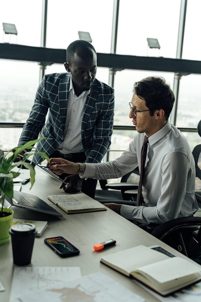 services-01 Two businessmen discussing projects in a modern high-rise office setting.