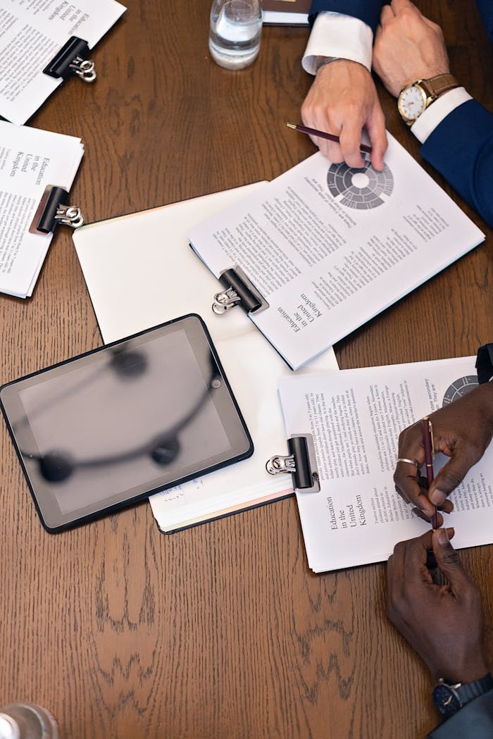 hero-img-02 Top view of a business meeting with hands, tablets, and documents on a table.